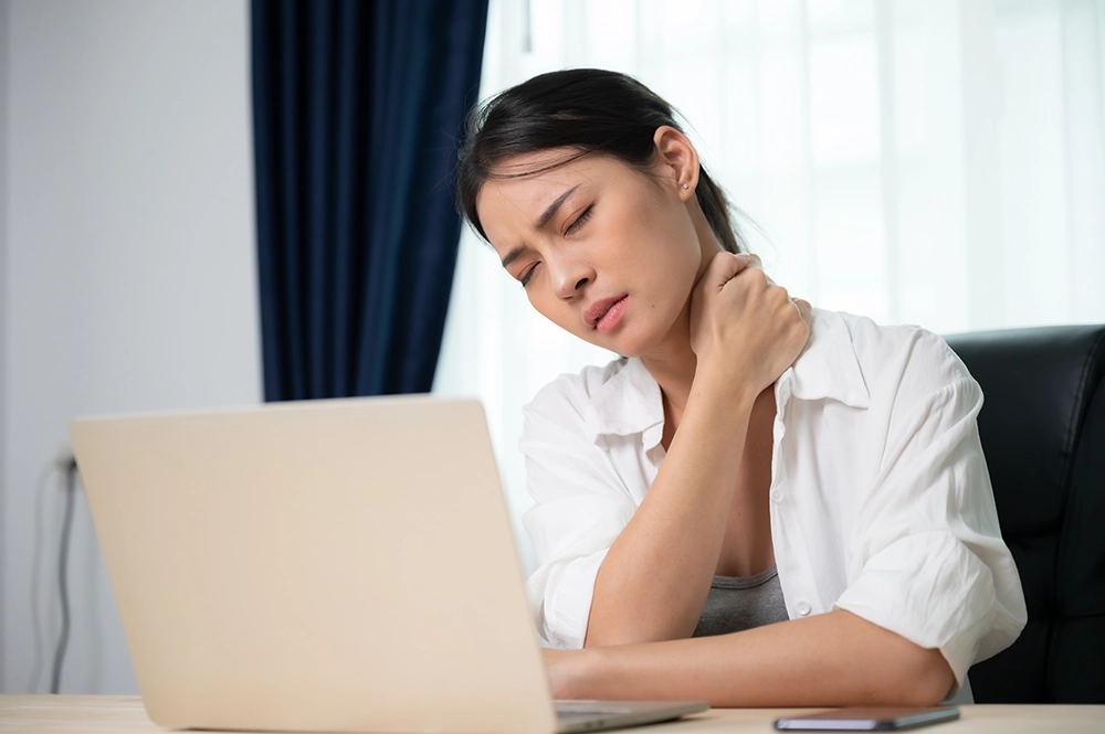 Woman experiencing neck pain and muscle tension caused by stress.